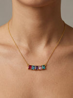 18k gold plated necklace with colorful gemstones on a person's neck against a neutral background
