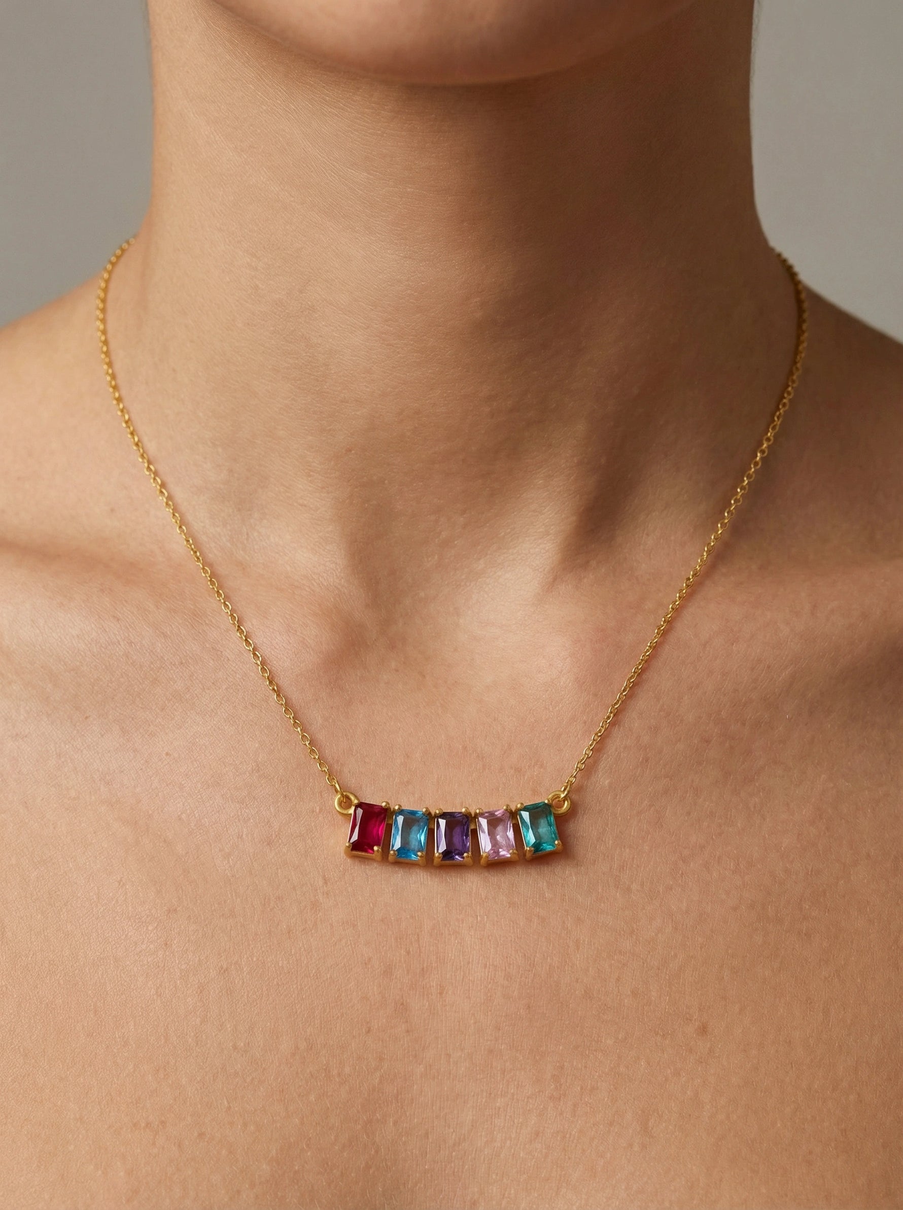 18k gold plated necklace with colorful gemstones on a person's neck against a neutral background