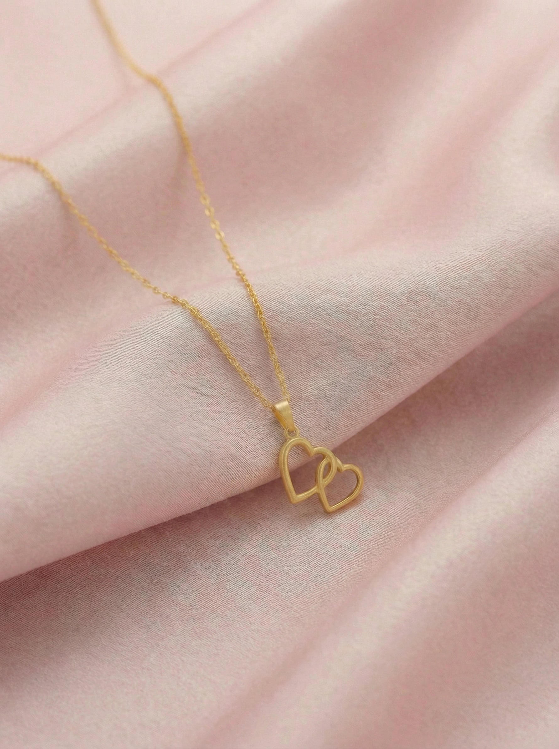 18k Gold plated necklace with a heart pendant on a pink fabric background