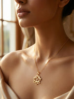 Close-up of a woman wearing a 18k gold plated necklace with a lotus flower pendant.