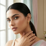 Woman wearing 18k gold plated earrings in a softly lit room