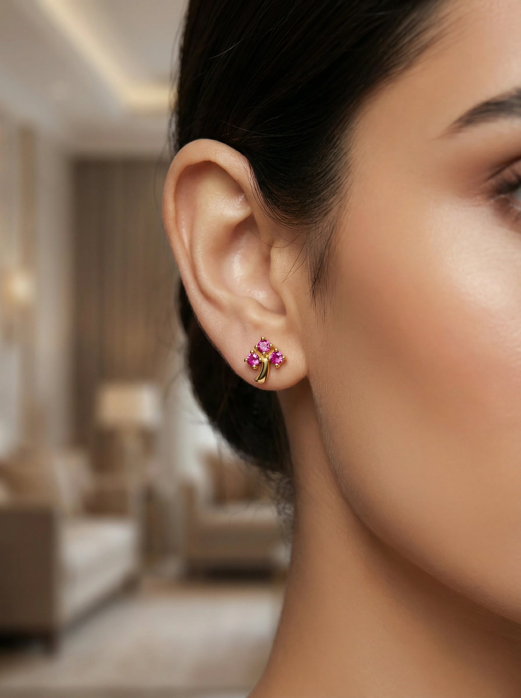 Close-up of a woman wearing a floral 18k gold plated earring in an indoor setting