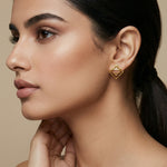 Close-up of a woman wearing 18k gold plated earrings with a neutral background