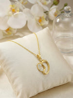 18k Gold plated necklace with a heart-shaped pendant on a beige cushion with flowers in the background