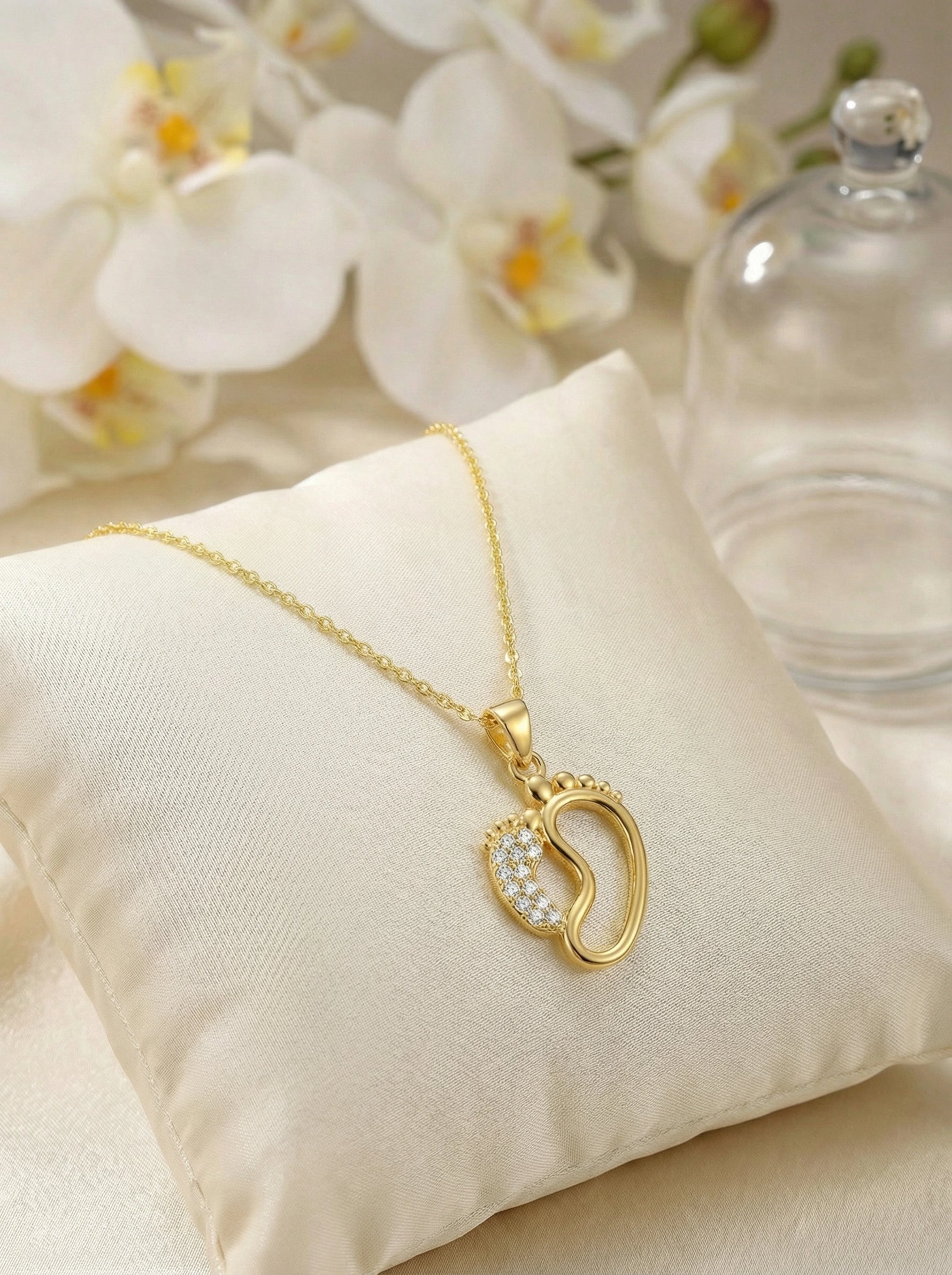 18k Gold plated necklace with a heart-shaped pendant on a beige cushion with flowers in the background