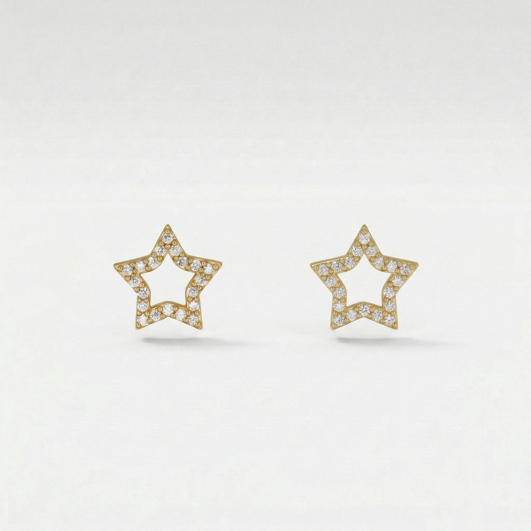 Star-shaped 18k gold plated earrings with diamond accents on a light gray background
