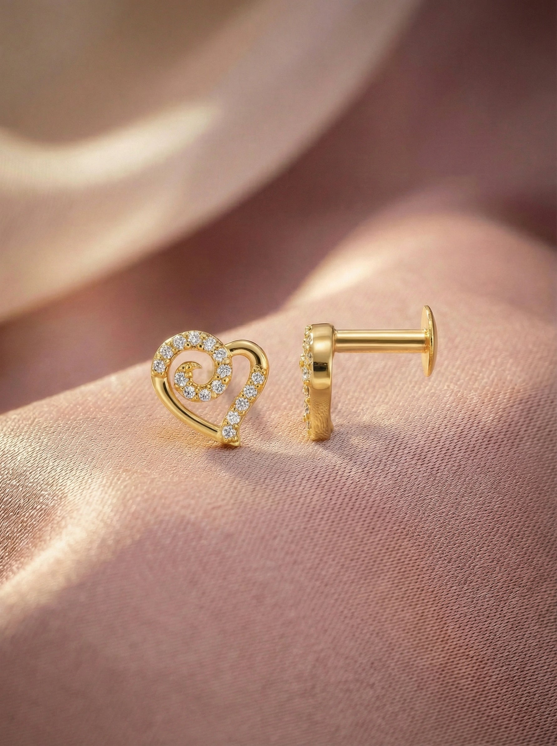 18k Gold plated heart-shaped earring on a person's ear with a soft pink background