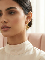Close-up of a woman wearing 18k gold plated  earrings with a blurred background