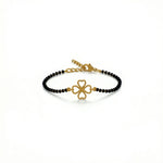Gold bracelet with black beads and clover charm on a white background