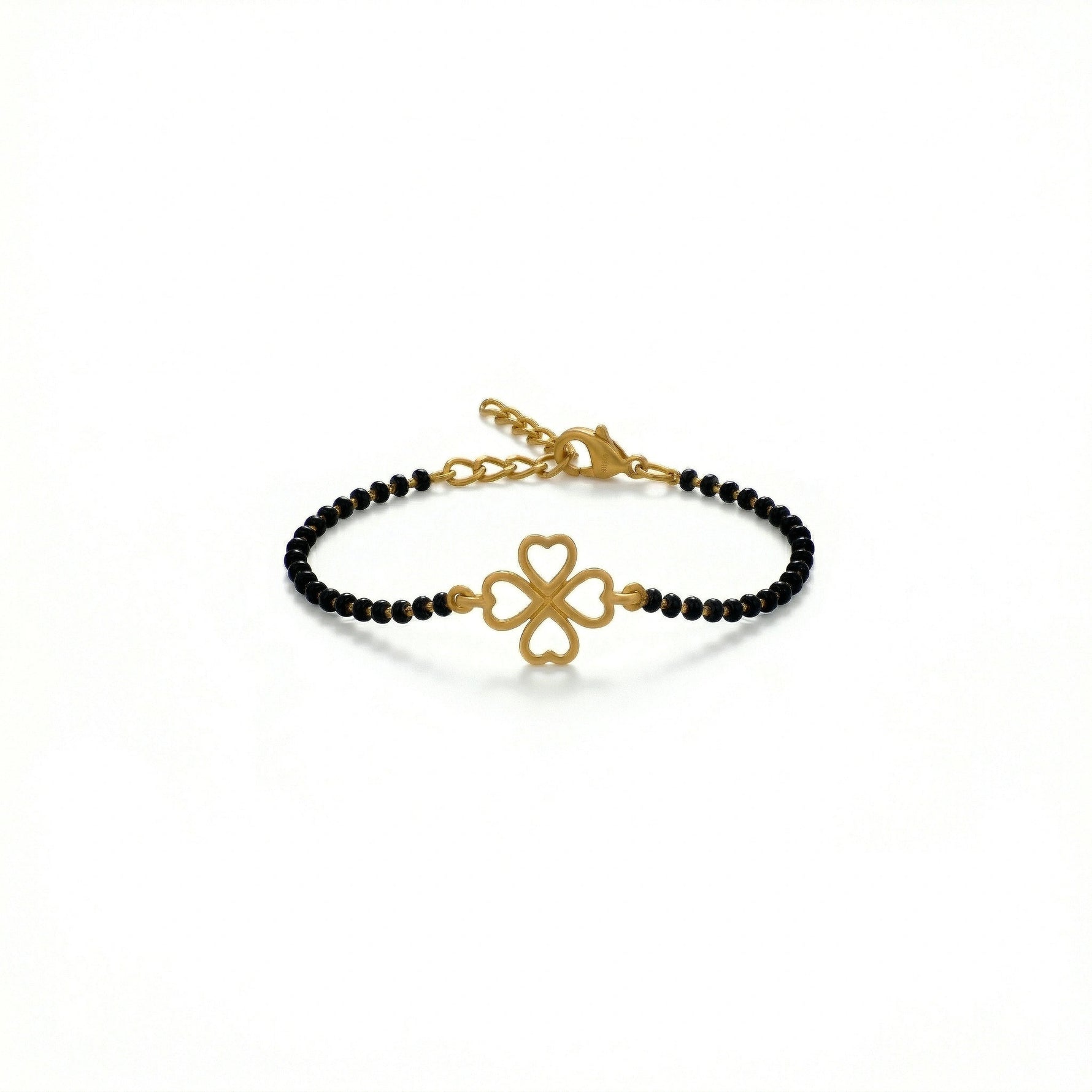 Gold bracelet with black beads and clover charm on a white background
