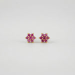Pair of flower-shaped 18k gold plated  earrings with pink stones on a light gray background