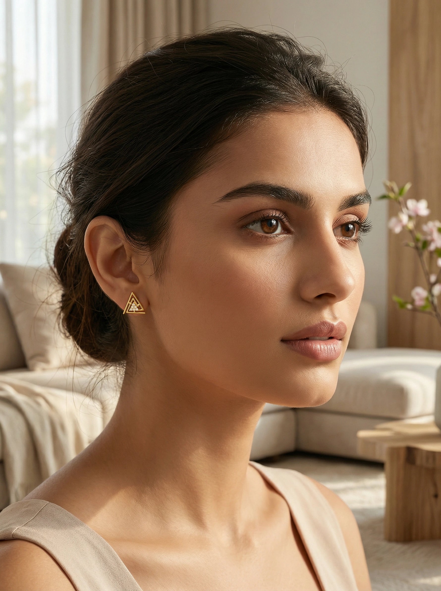 Woman wearing 18k gold plated  triangle earrings in a living room setting
