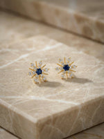 18k Gold plated earrings with blue gemstones on a marble surface
