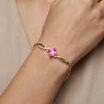 18k Gold plated bracelet with a pink gemstone on a wrist against a beige background