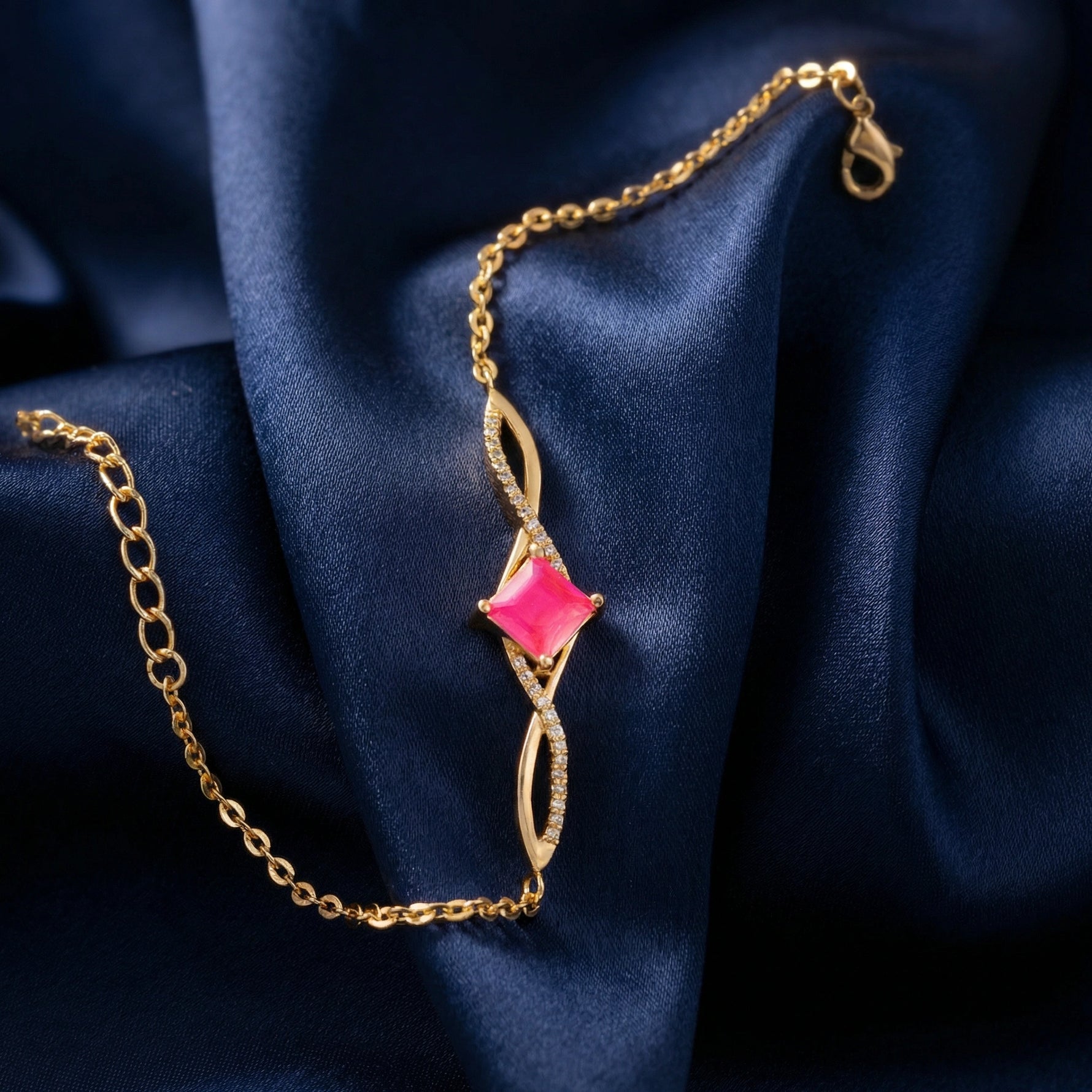 18k Gold plated bracelet with a pink gemstone on a blue fabric background