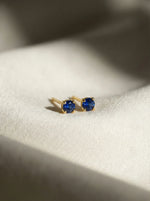 18k Gold plated earrings with blue gemstones on a white fabric background