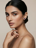 Woman wearing a blue earring 18k gold plated against a beige background