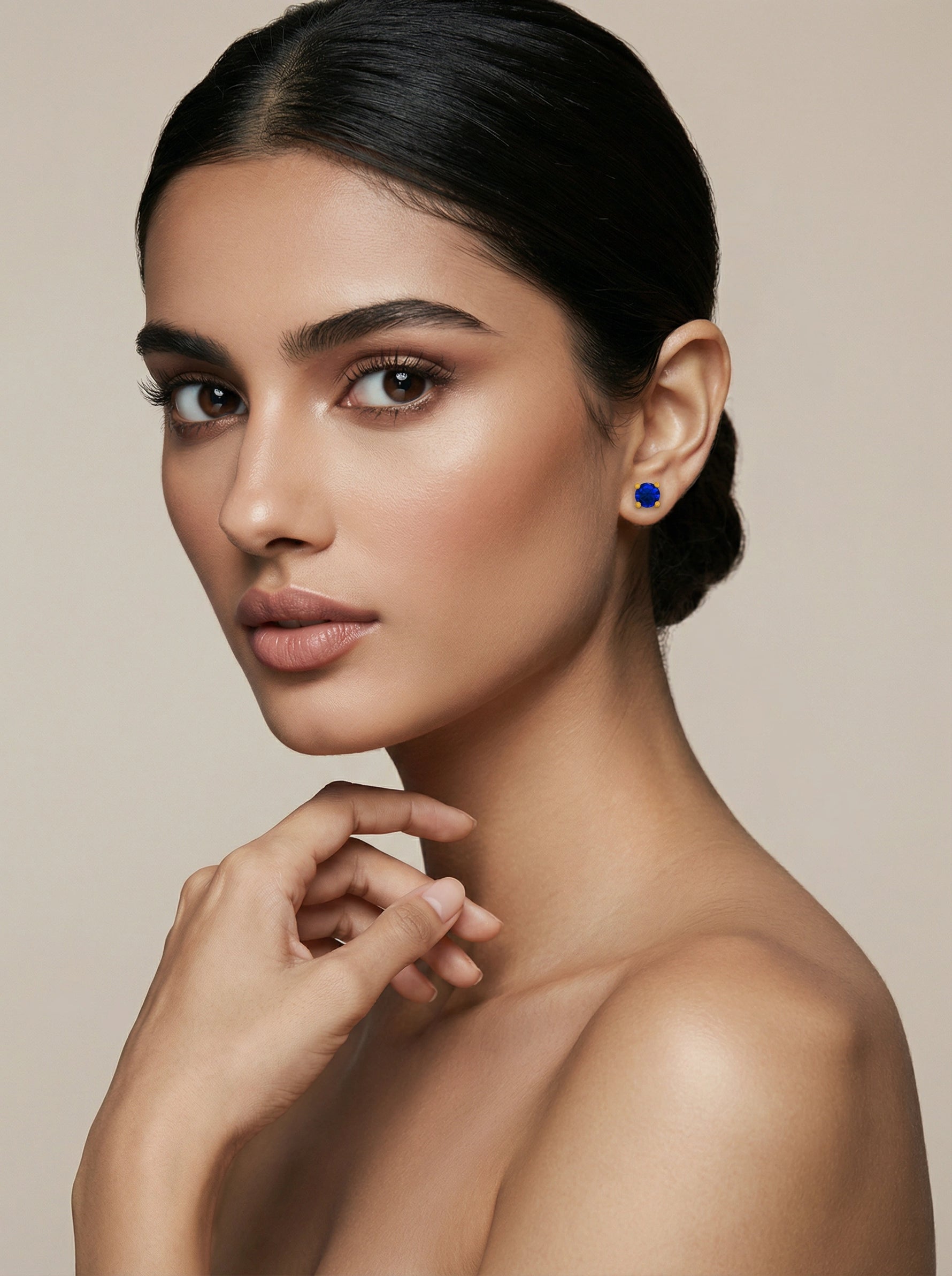 Woman wearing a blue earring 18k gold plated against a beige background