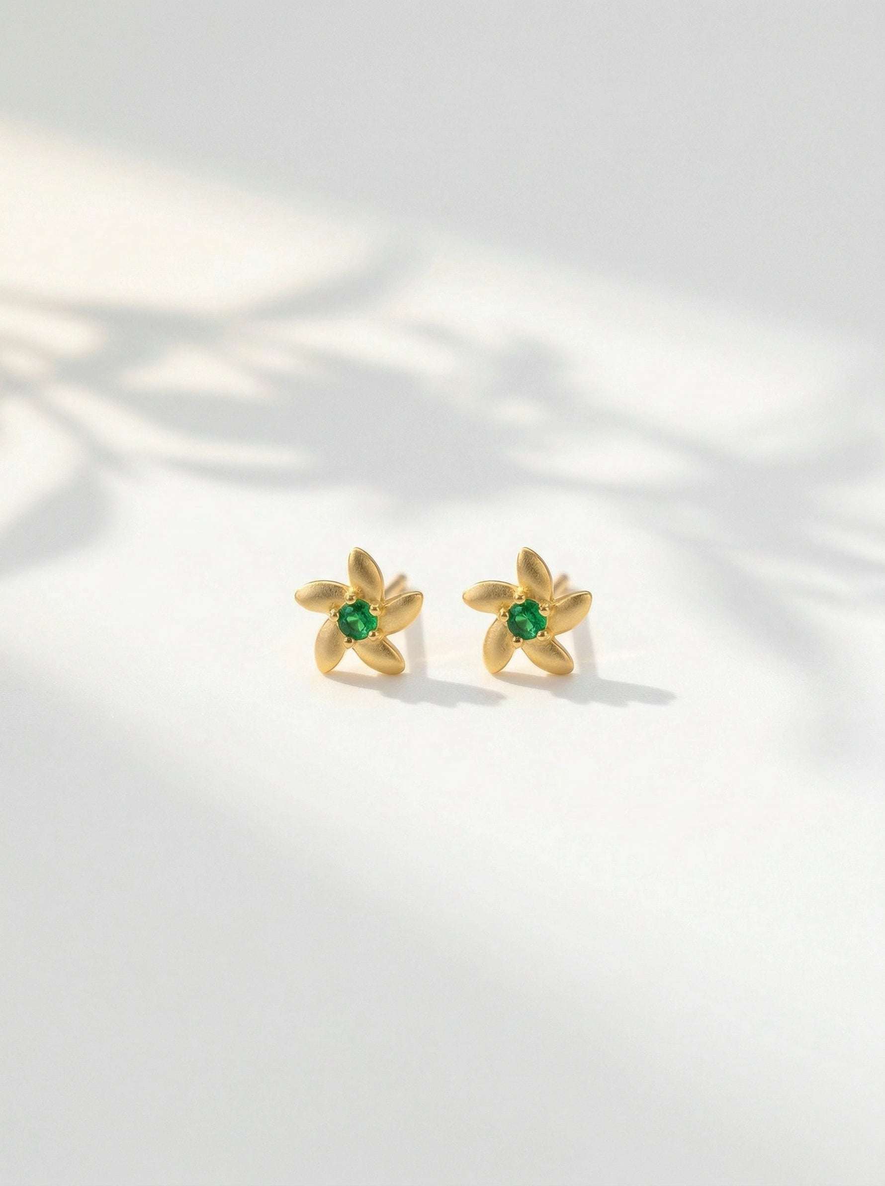 18k Gold plated  earrings with green gemstones on a light background