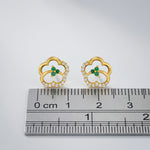 18k Gold plated earrings with green gemstones and clear stones on a ruler for scale.