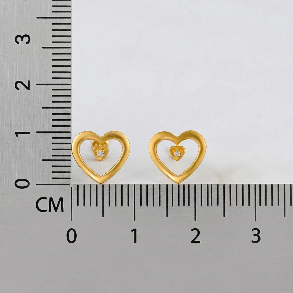 18k Gold plated heart-shaped earrings with embedded diamonds next to a ruler for scale on a white background