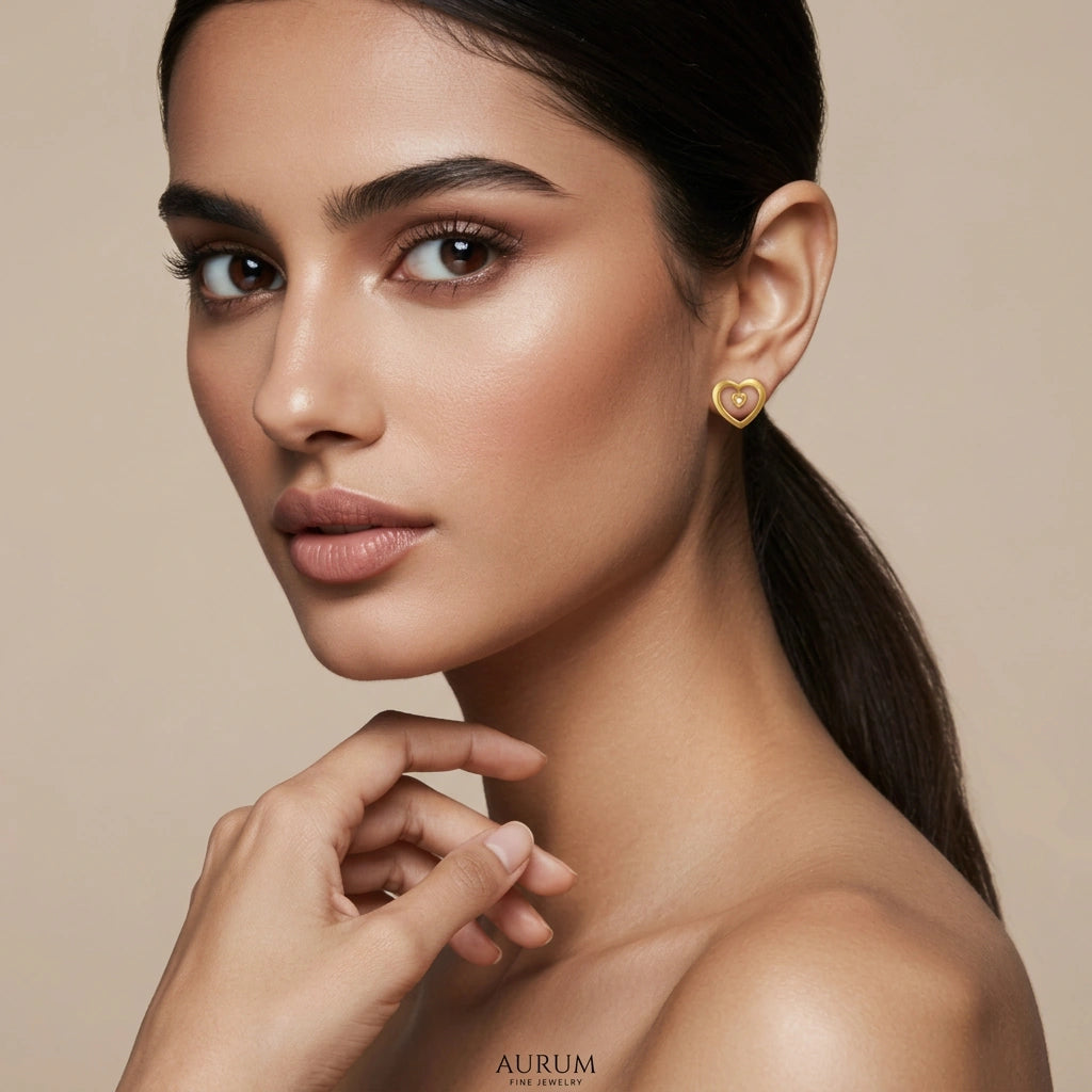 Woman wearing 18k gold plated heart-shaped earrings with a neutral background