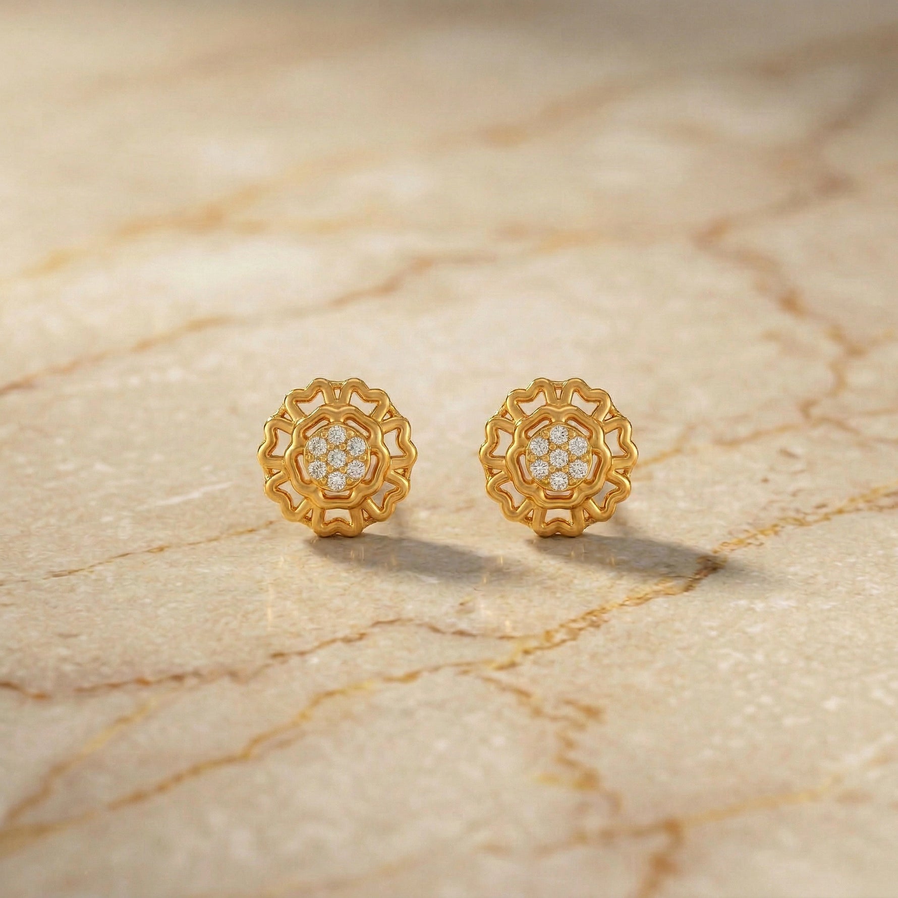 Pair of 18k gold plated earrings with diamond accents on a marble surface