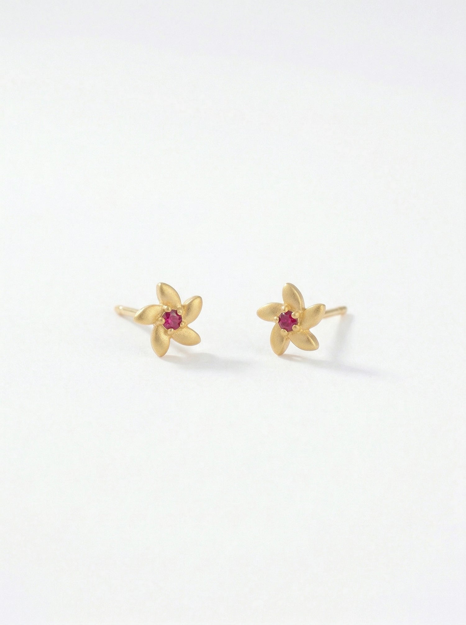 18k Gold plated flower-shaped earrings with red gemstones on a white background