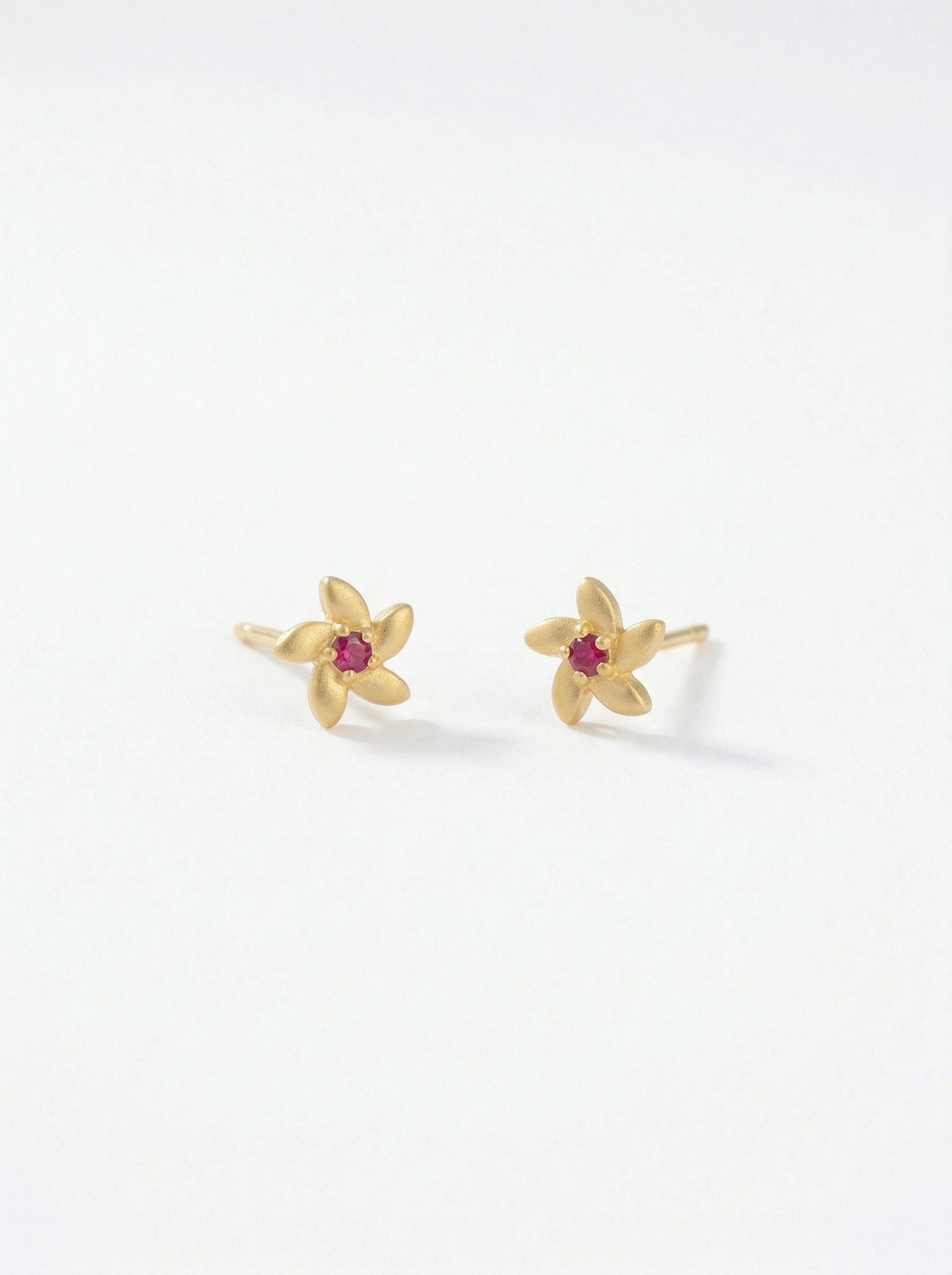 18k Gold plated flower-shaped earrings with red gemstones on a white background