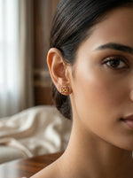 Close-up of a woman wearing 18k gold plated earrings with a blurred background