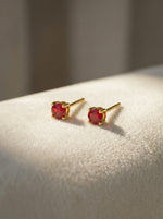 18k Gold plated earrings with red gemstones on a light surface