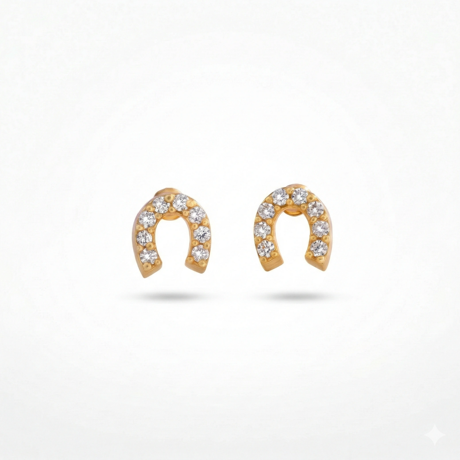 Gold horseshoe-shaped earrings with embedded stones on a white background