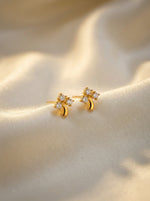 18k Gold plated earrings with diamond accents on a soft beige fabric background