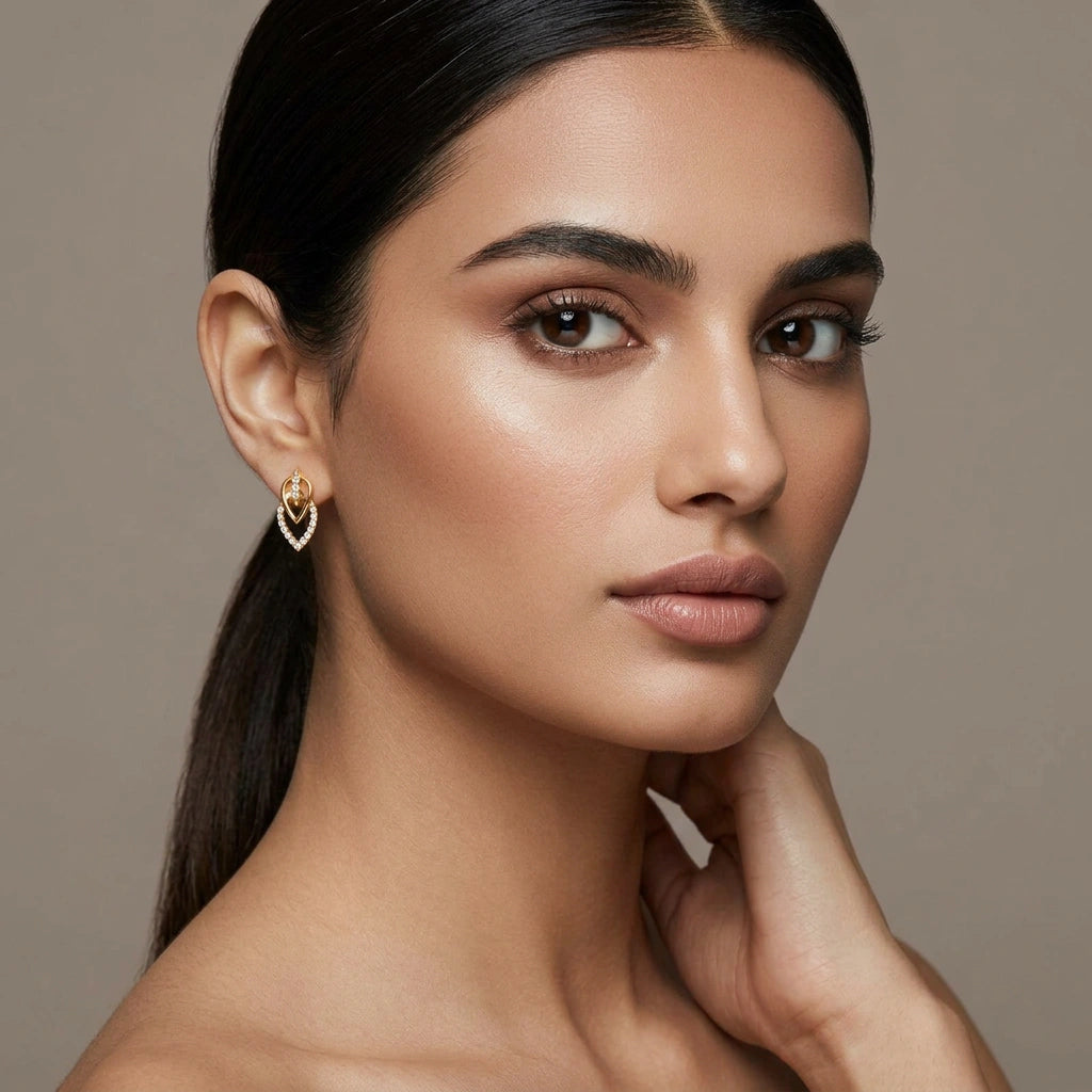 Woman wearing 18k gold plated heart-shaped earrings against a neutral background