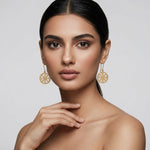 Woman wearing 18k gold plated earrings against a plain background