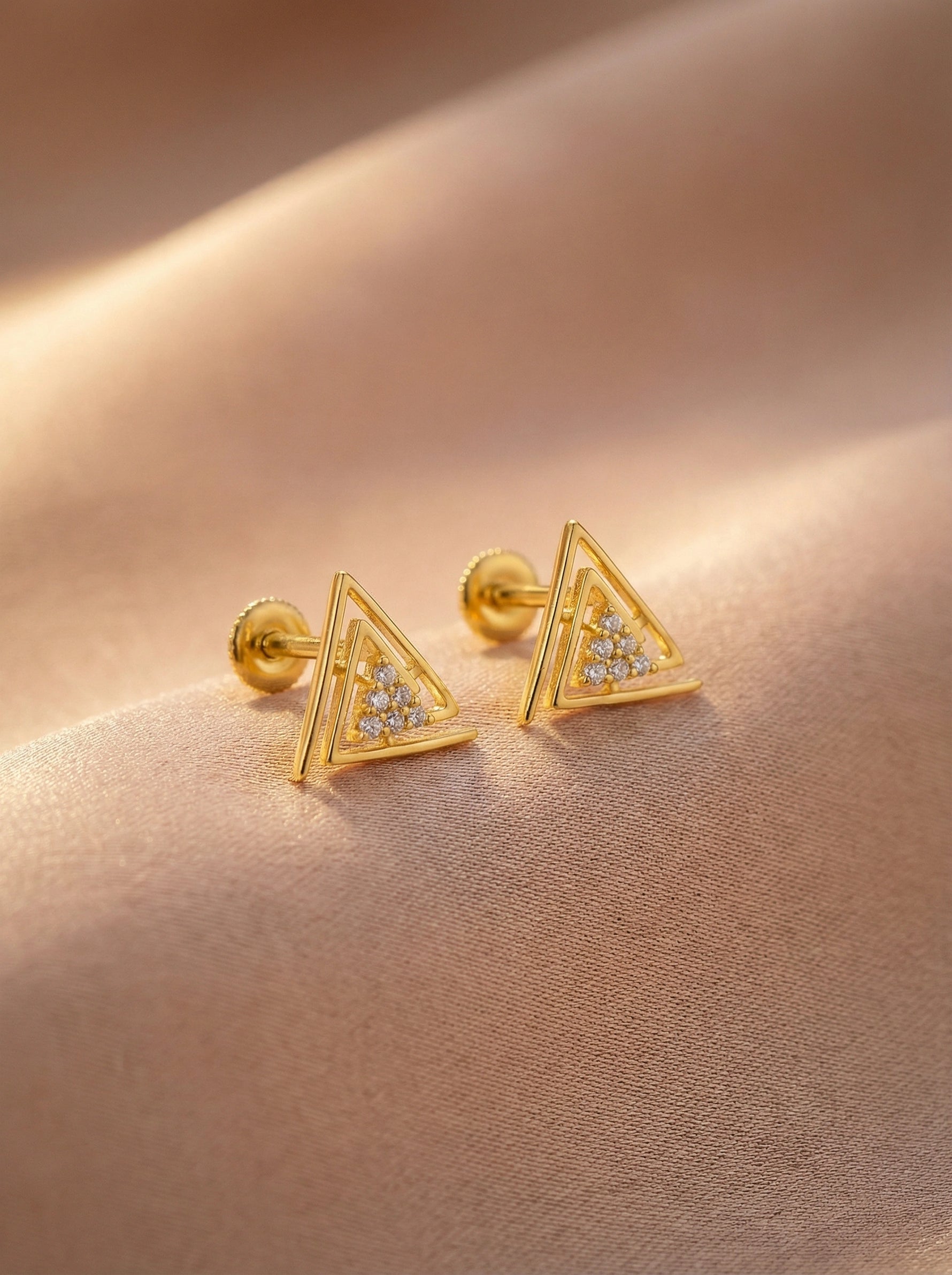 18k Gold plated  triangle-shaped earrings with embedded stones on a beige fabric background