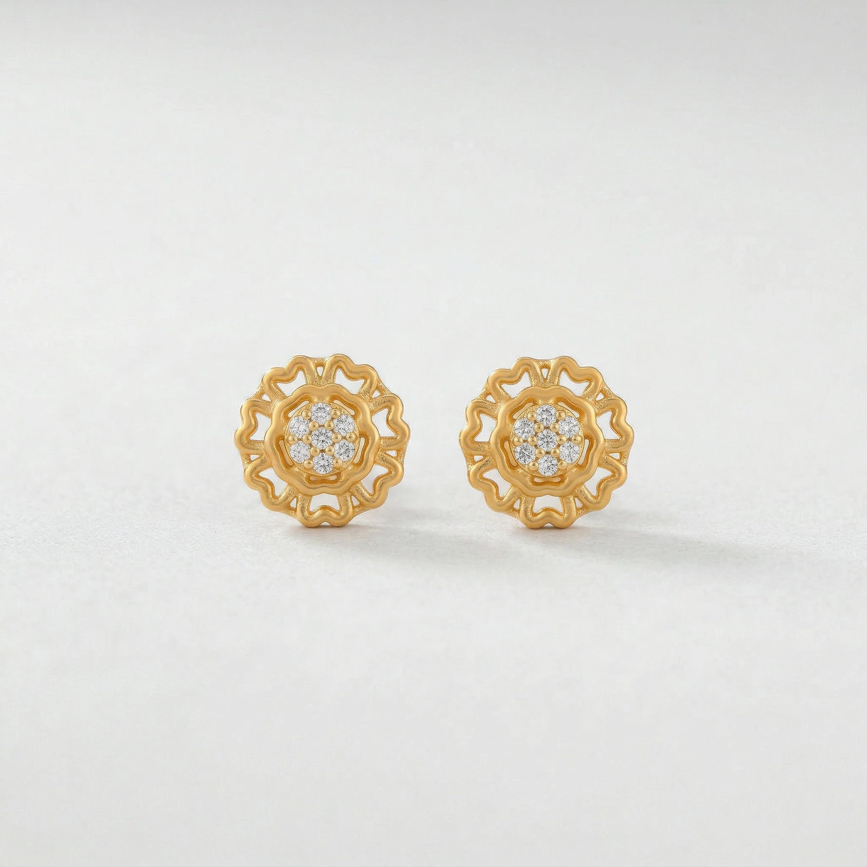 Pair of 18k gold plated earrings with diamond accents on a light gray background