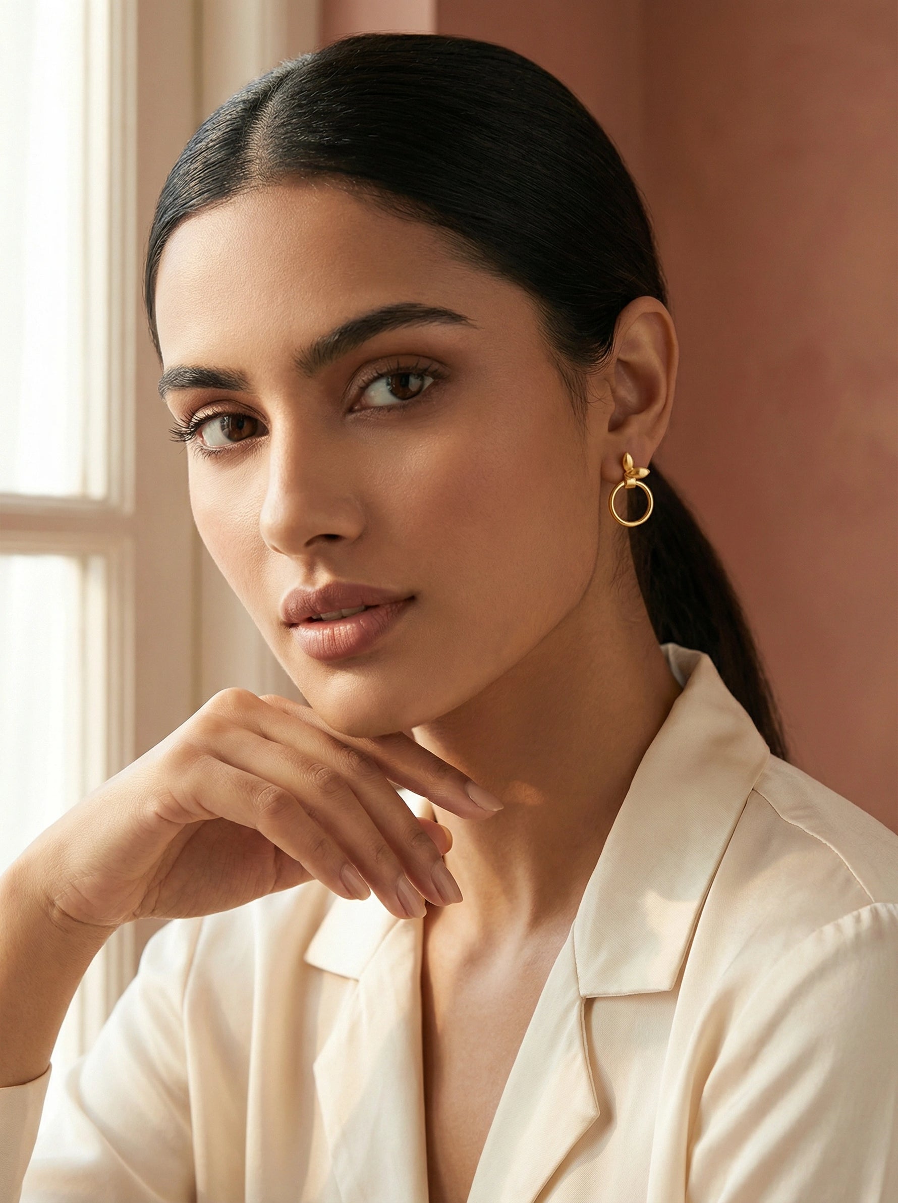 Woman wearing 18k gold plated earrings with a neutral background