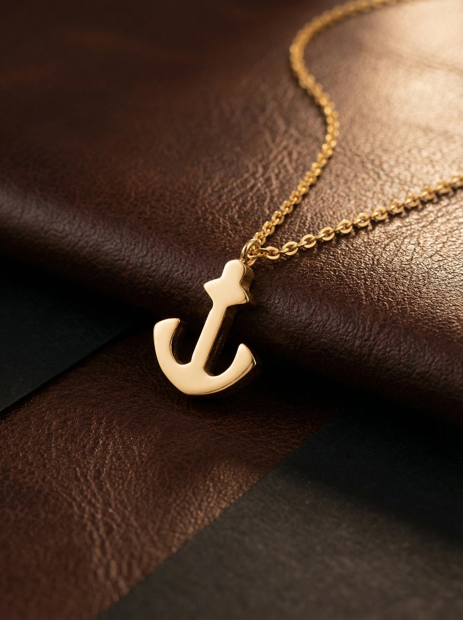 18k Gold plated anchor necklace on a brown leather surface