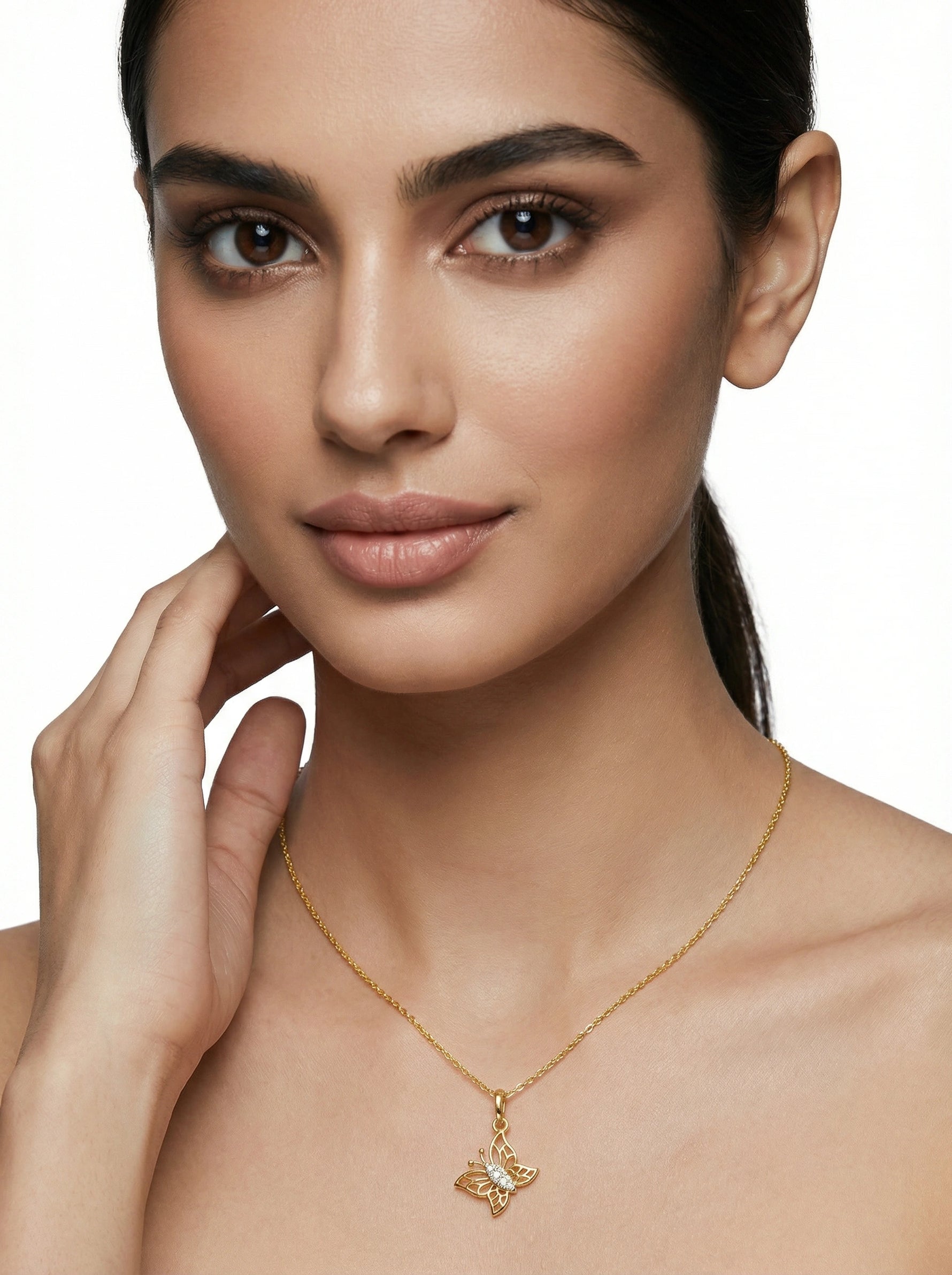 Woman wearing a 18k gold plated necklace with a butterfly pendant on a neutral background