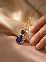 18k Gold plated necklace with blue teardrop-shaped gemstones on a soft beige background
