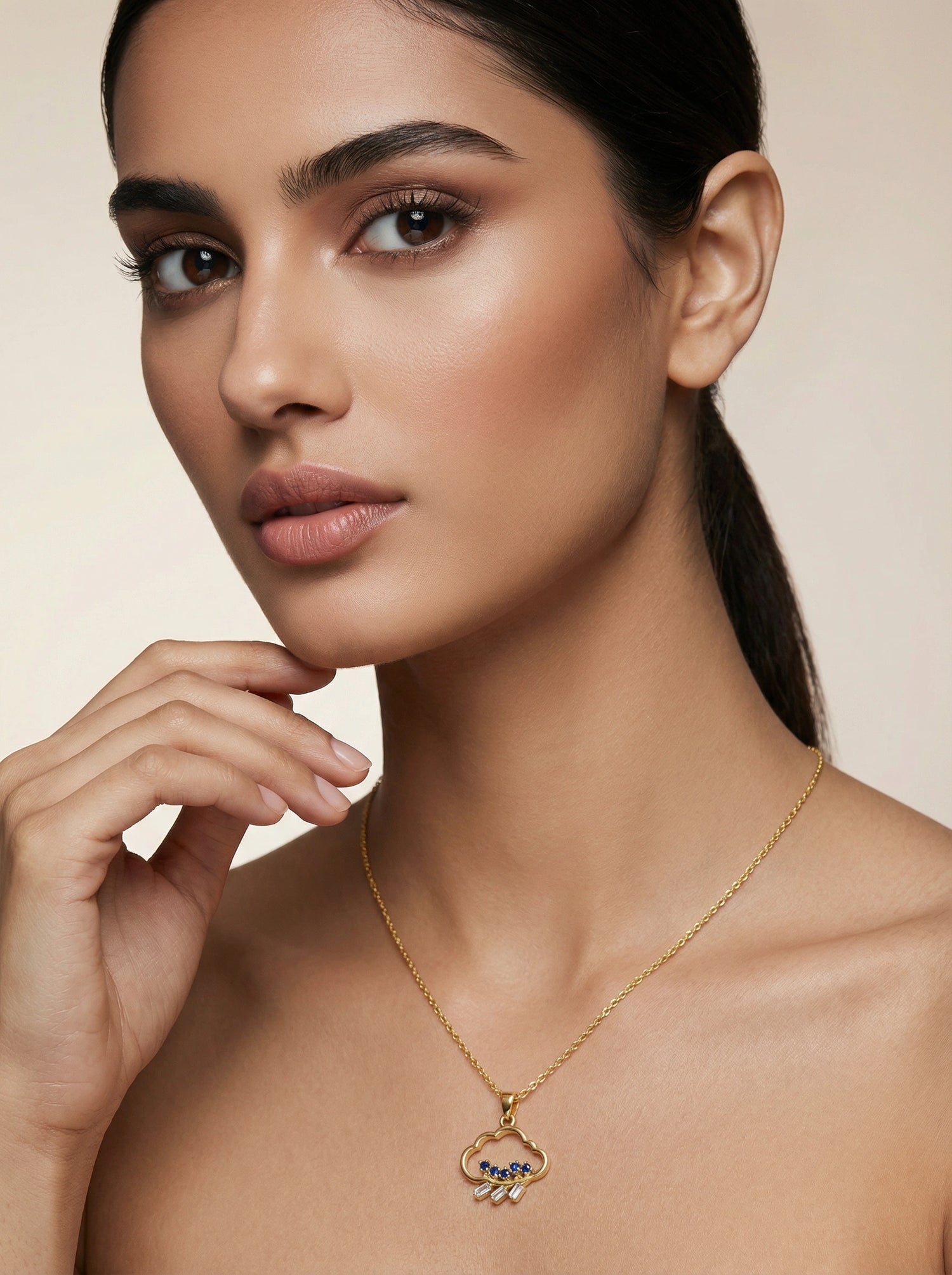 Woman wearing a18k gold plated necklace with a pendant against a neutral background
