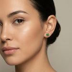 Close-up of a woman wearing green 18k gold plated earrings with a neutral background