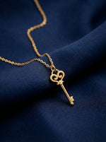 18k Gold plated key necklace on a blue fabric background