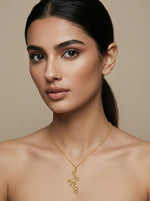 Woman wearing a 18k gold plated necklace against a beige background