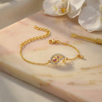 18k Gold plated bracelet with a decorative clasp on a marble surface with flowers in the background