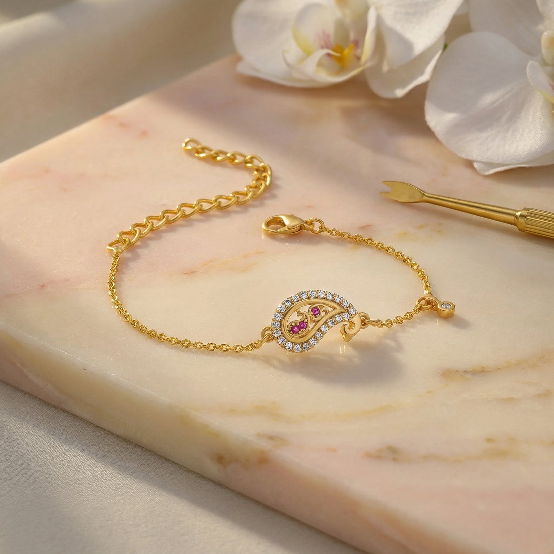 18k Gold plated bracelet with a decorative clasp on a marble surface with flowers in the background