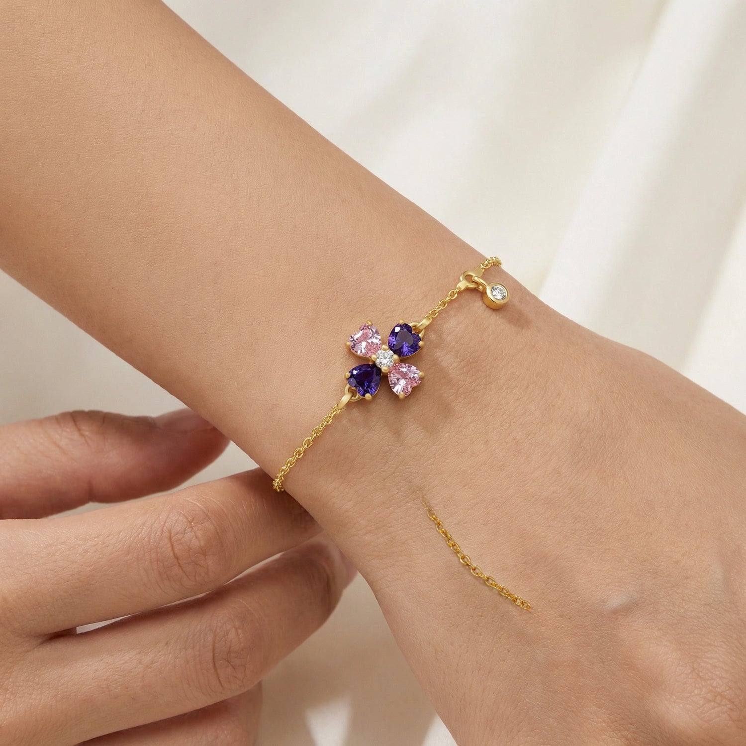 18k Gold plated bracelet with floral design featuring pink and purple stones on a wrist.
