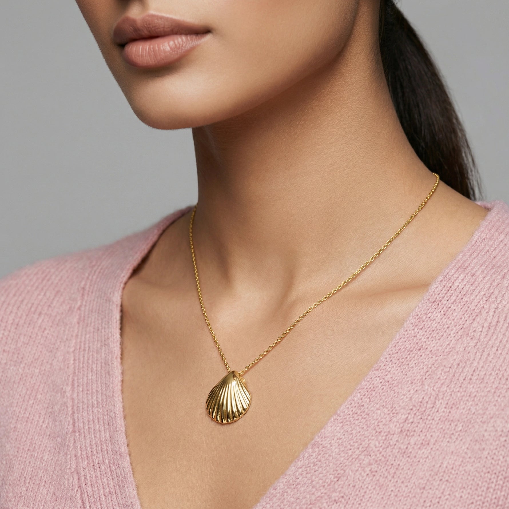 18k Gold plated necklace with a shell pendant worn by a person in a pink sweater.