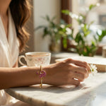 Person holding a flower with 18k gold plated  bracelet on a table in a bright room with plants